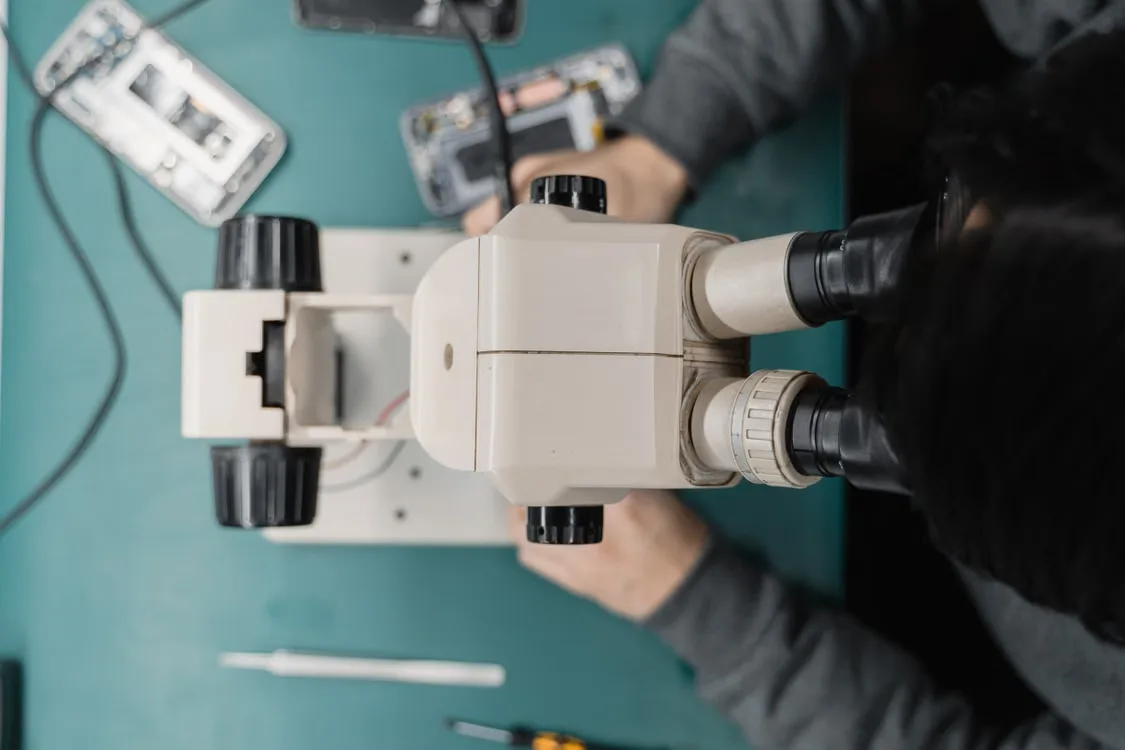 Primo piano di un microscopio durante la riparazione precisa di uno smartphone.